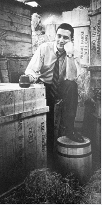 Photo of Gordon Segal surrounded by crates and barrels.